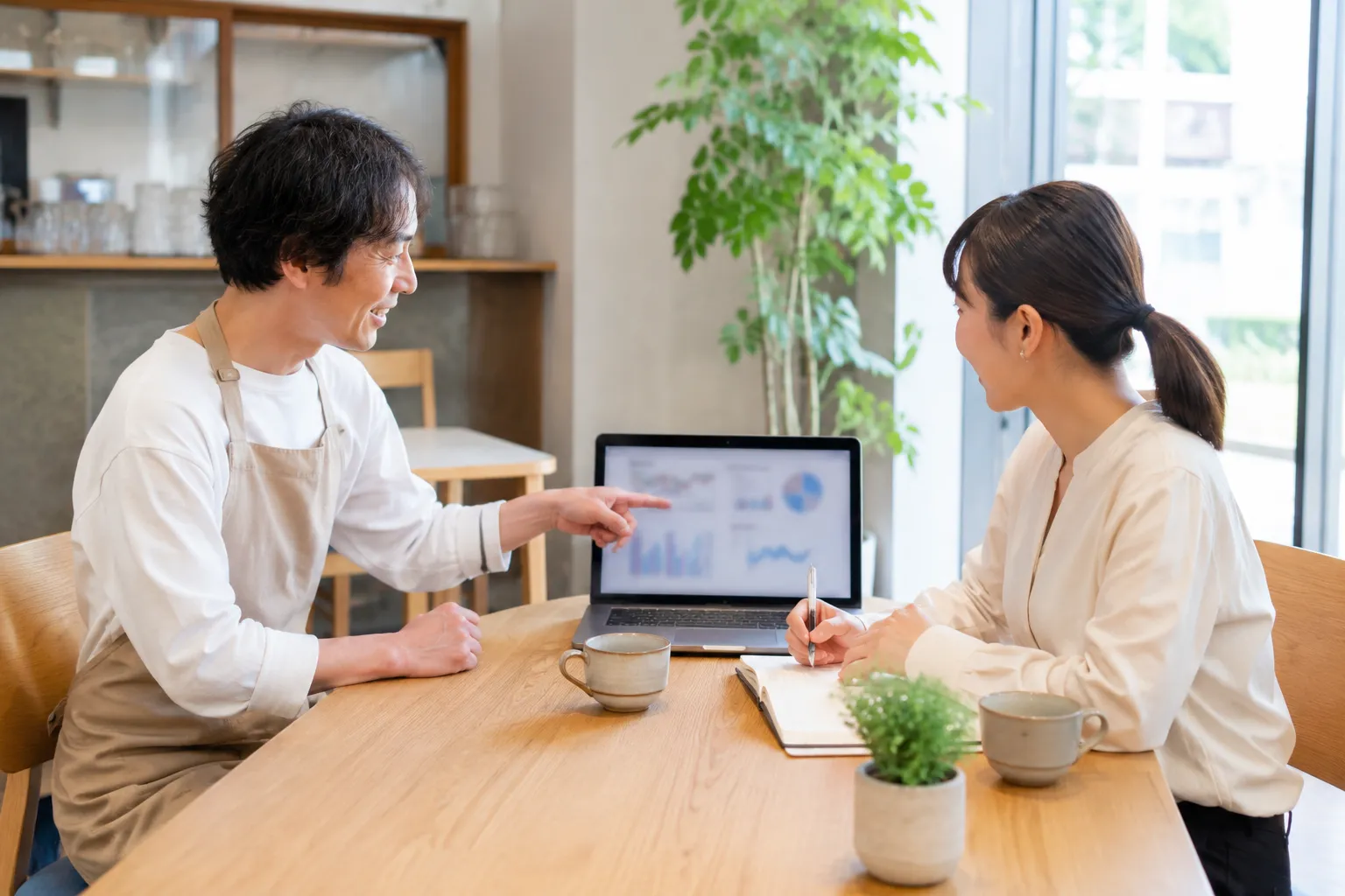 カフェでノートパソコンを見ながら相談する打ち合わせの様子